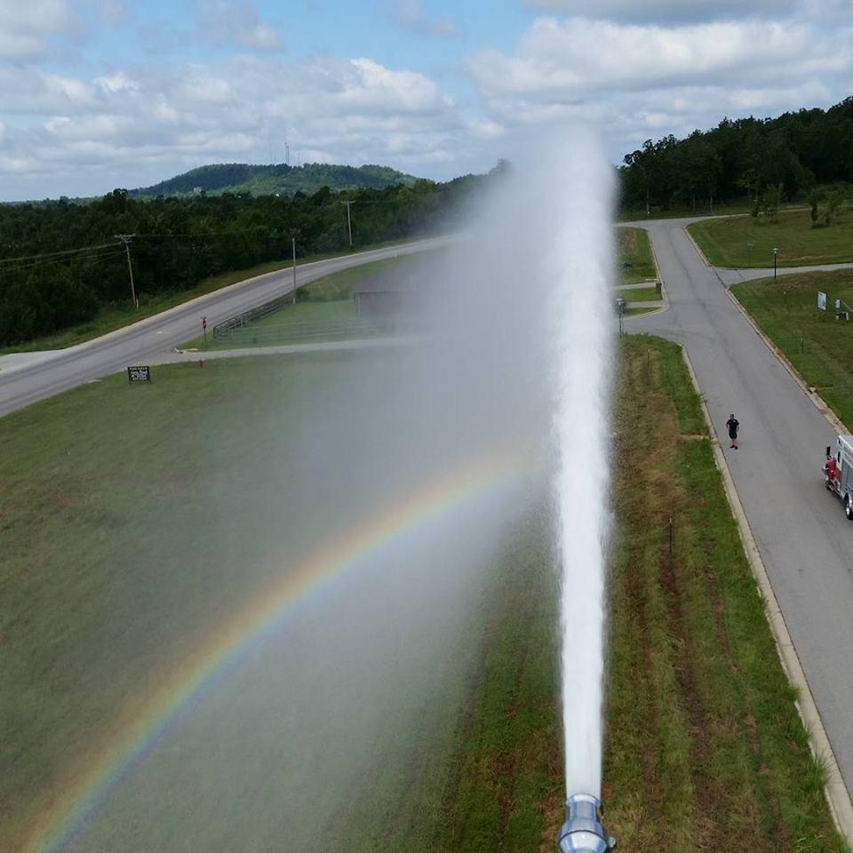 water spraying from fire engine, creating a rainbow in the mist