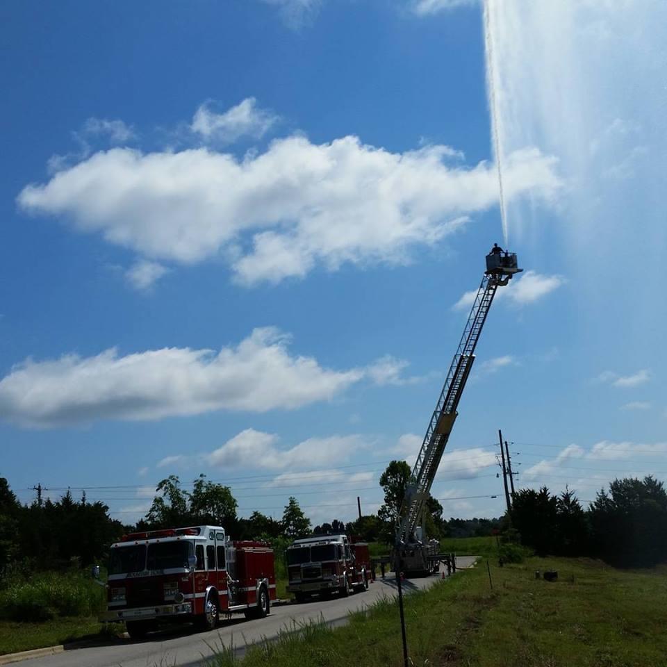 water spraying from top of fire engine ladder during tower truck training