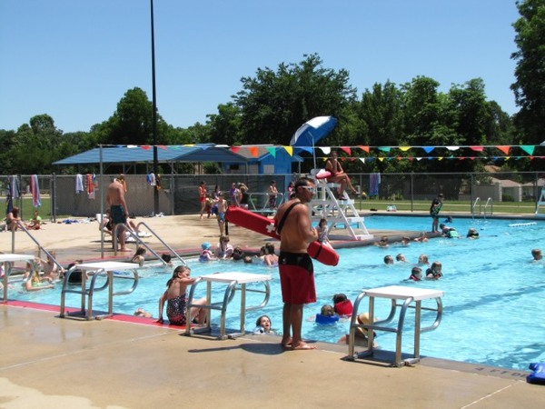 A lifeguard standing watch over children at the pool on a sunny day. 
